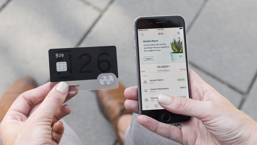 Man holding N26 bank card and a phone with the N26 bank app open.